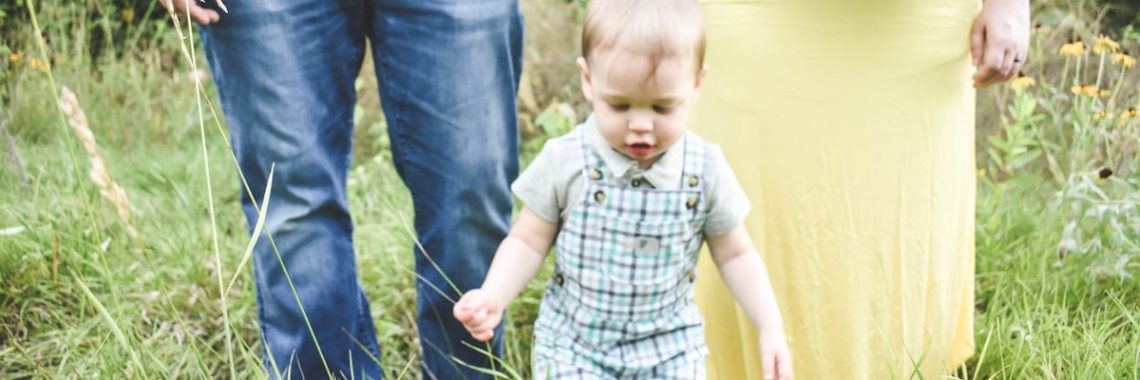 man in black tank top carrying baby in blue and white plaid button up shirt