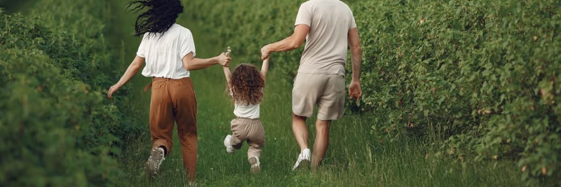 A joyful family strolls through a lush green field, enjoying quality time together.